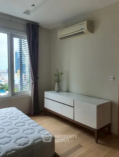 Modern bedroom with air conditioning and city view, featuring sleek furniture and natural light.