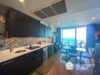 Modern kitchen with ocean view and open layout, featuring sleek cabinetry and dining area.