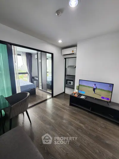 Modern living room with open layout and view into cozy bedroom, featuring sleek furniture and natural light.