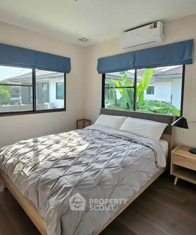 Cozy bedroom with large windows and modern decor in a bright, airy home.