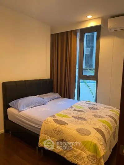 Cozy bedroom with modern decor and large window offering natural light in a stylish apartment.