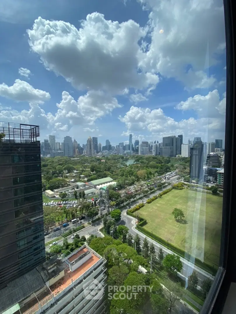 Stunning cityscape view from high-rise building window showcasing urban skyline and lush greenery.