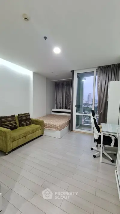 Modern studio apartment with city view, featuring a cozy bed, stylish sofa, and workspace.