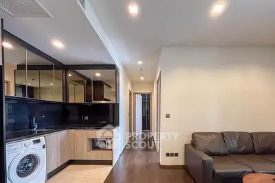 Modern living room with integrated kitchen and washing machine, sleek design and cozy ambiance.