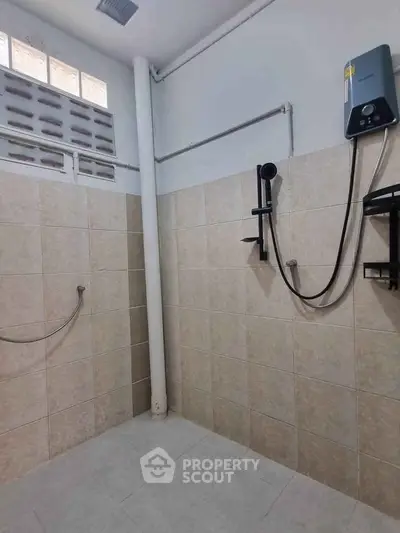 Spacious bathroom with tiled walls and modern shower fixtures, ideal for a refreshing experience.