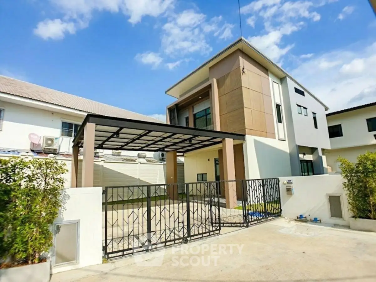 Modern two-story house with gated entrance and carport in a suburban neighborhood.