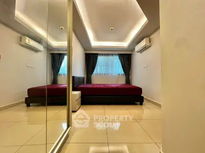 Spacious bedroom with modern design, mirrored closet, and ambient lighting for a luxurious feel.