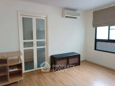 Spacious room with wooden flooring, sliding door, and air conditioning unit.