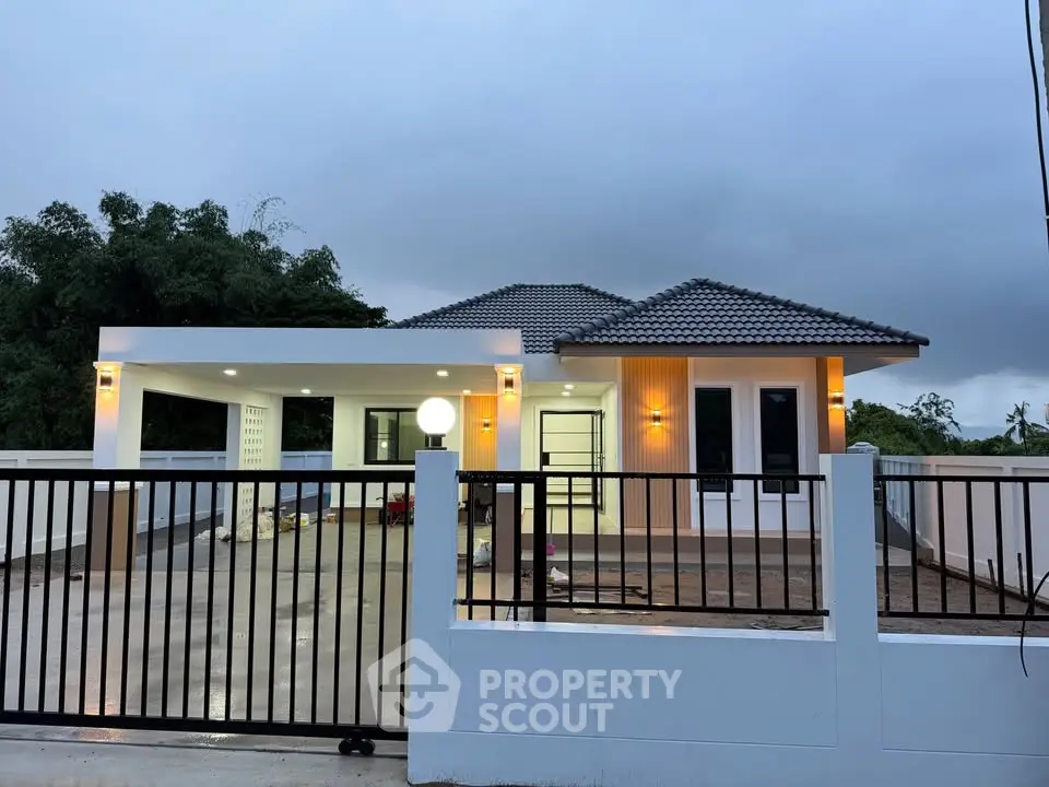 Modern single-story house with gated entrance and stylish exterior lighting.