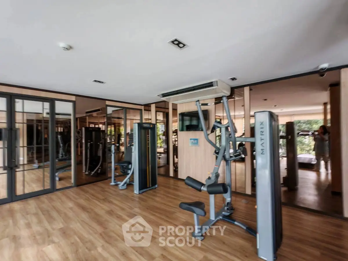 Spacious modern gym with state-of-the-art equipment and mirrored walls in a luxury residential building.