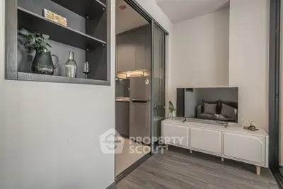 Modern living room with sleek design and integrated kitchen area, featuring stylish shelving and contemporary decor.
