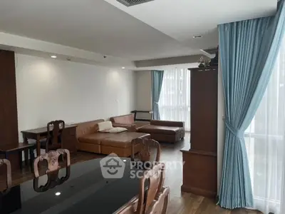 Spacious living room with elegant wooden furniture and large windows with blue curtains