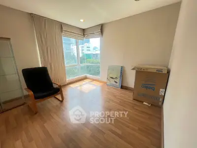 Bright and airy room with large window and wooden flooring, perfect for a cozy living space.