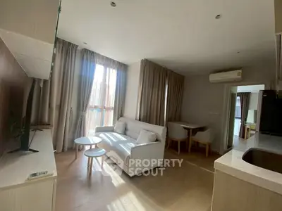 Modern living room with natural light and cozy furniture, featuring a sleek open layout.