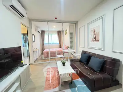 Modern living room with stylish decor and view into cozy bedroom through glass partition.