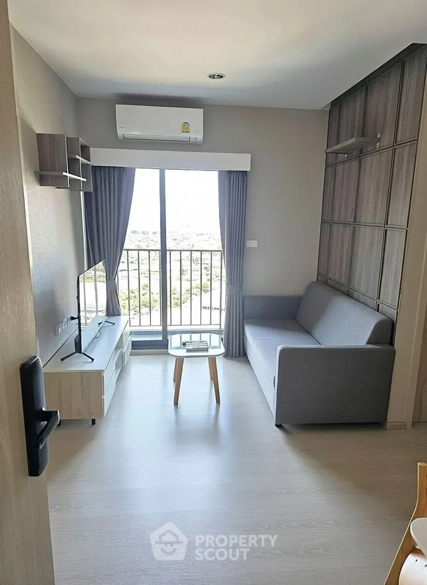 Modern living room with balcony view, featuring sleek furniture and ample natural light.