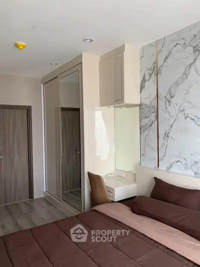 Modern bedroom with stylish marble accent wall and cozy bedding
