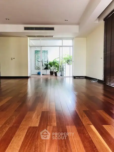 Spacious living room with wooden flooring and large windows for natural light.