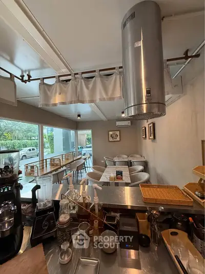 Chic modern cafe interior with stainless steel kitchen and cozy seating area, perfect for urban dining.