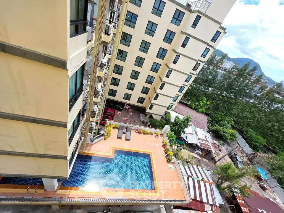 Stunning aerial view of modern apartment building with inviting pool and lush surroundings.
