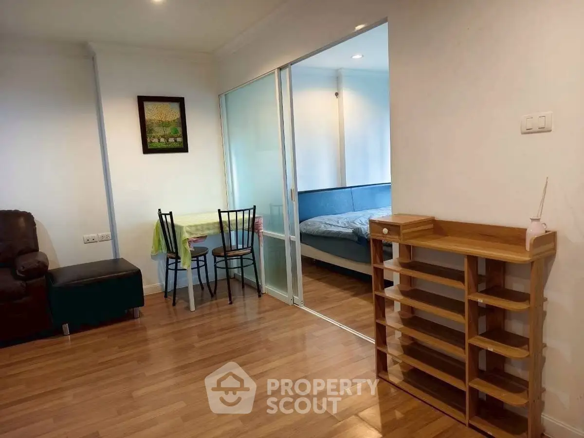 Cozy apartment with wooden flooring and sliding glass doors leading to a bedroom.