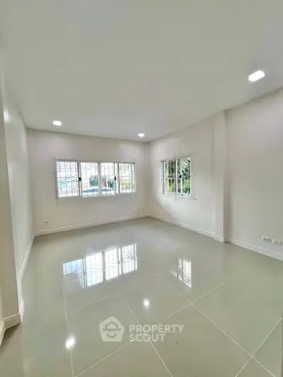 Spacious empty room with large windows and glossy tiled floor, perfect for customization.