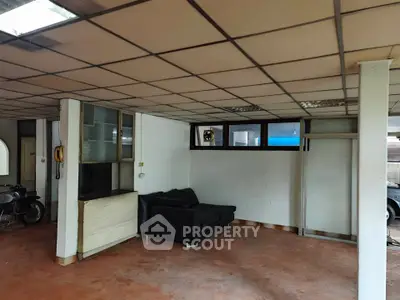 Spacious interior with tiled floor and black sofa, ideal for creative renovation.