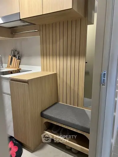 Modern kitchen with sleek wooden cabinetry and integrated seating area, perfect for compact living spaces.