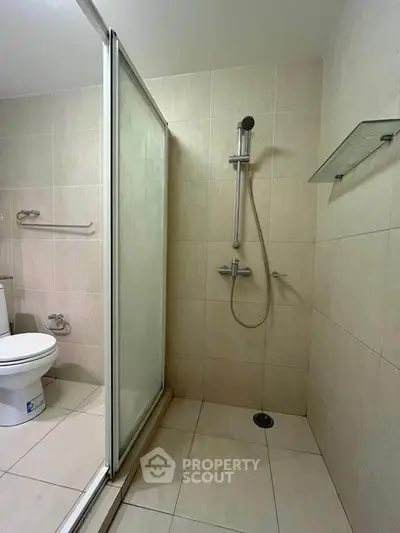 Modern bathroom with sleek shower and toilet in a minimalist design.