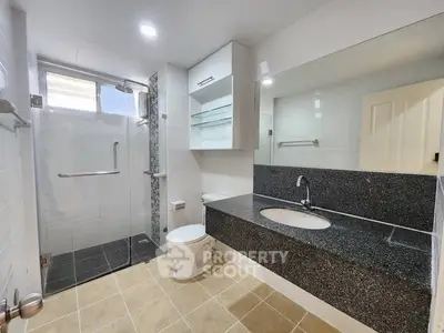 Modern bathroom with sleek design, featuring a spacious shower and elegant vanity.