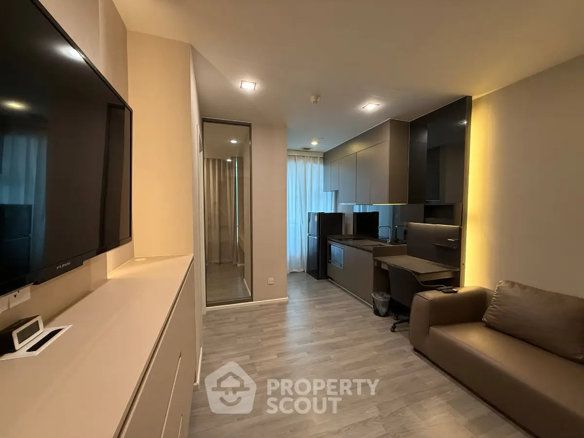 Modern apartment interior with sleek kitchen and cozy living area, featuring stylish furnishings and ambient lighting.