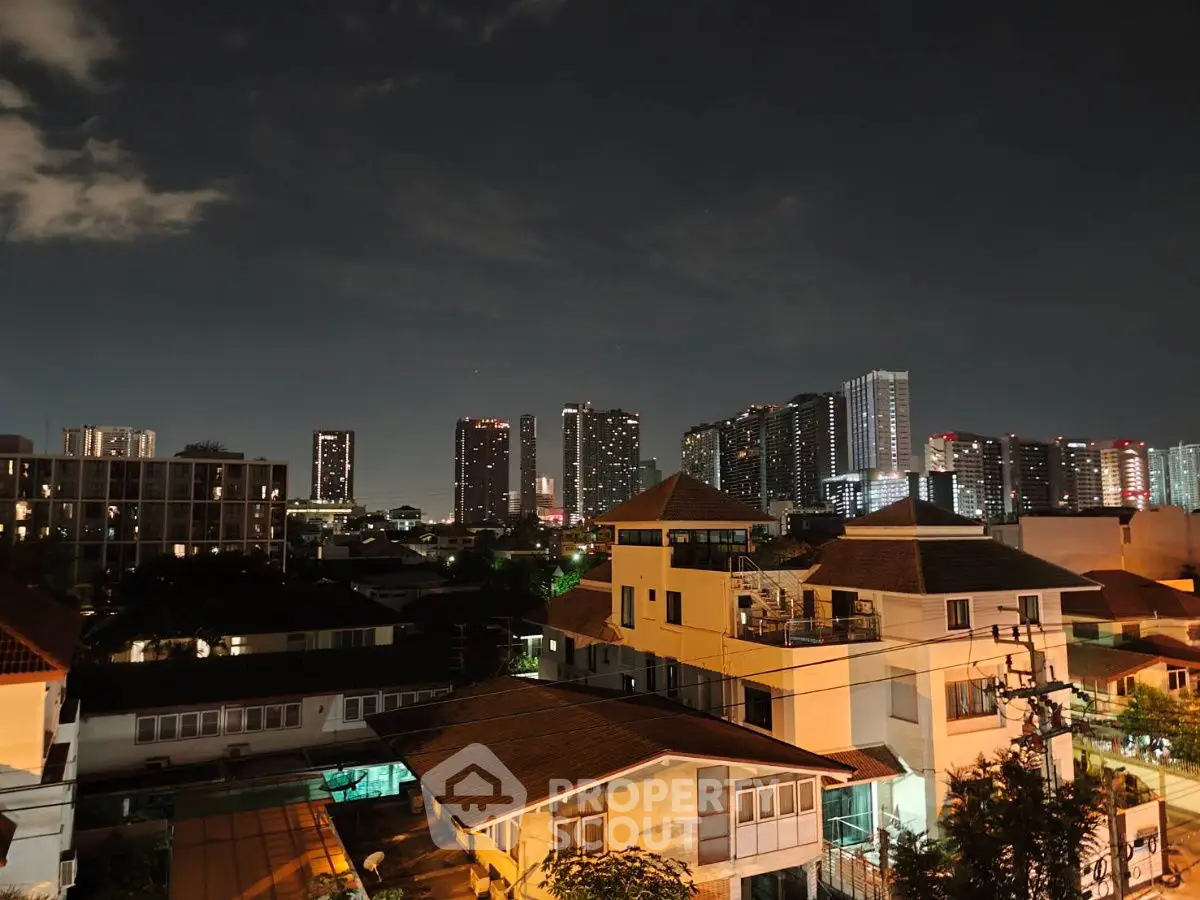 Stunning night cityscape view with illuminated buildings and residential rooftops.
