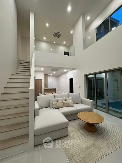Spacious modern living room with high ceilings and elegant staircase in a luxurious home.