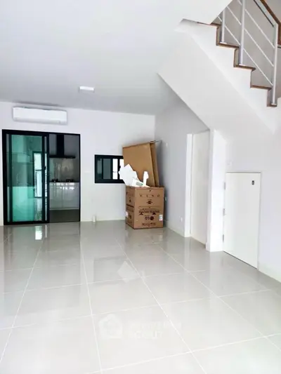 Spacious modern living room with sleek tile flooring and glass sliding doors.