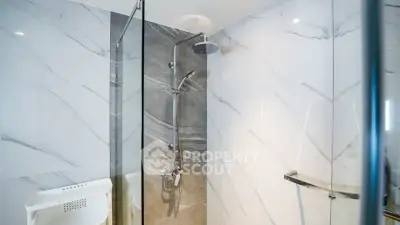 Modern bathroom with sleek marble tiles and glass shower enclosure