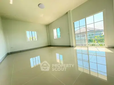 Spacious sunlit room with large windows and glossy tiled floor, perfect for modern living.