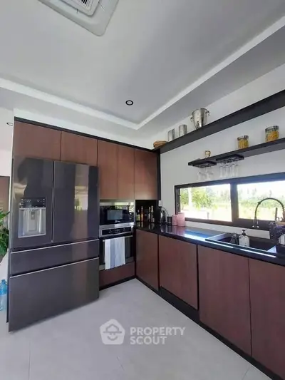 Spacious modern kitchen with sleek dark wood cabinetry, stainless steel appliances, and a large window offering ample natural light.