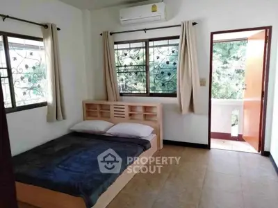 Cozy bedroom with natural light and balcony access in a serene setting.