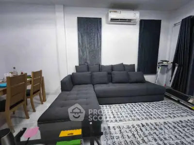 Modern living room with stylish gray sectional sofa and dining area, featuring air conditioning and contemporary decor.
