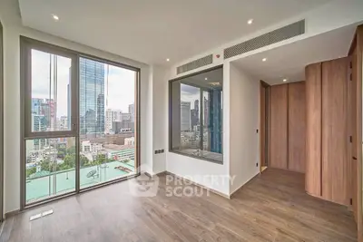 Modern apartment with floor-to-ceiling windows offering stunning city views and elegant wooden flooring.