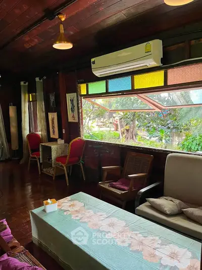 Charming living room with wooden decor and large window overlooking lush garden.