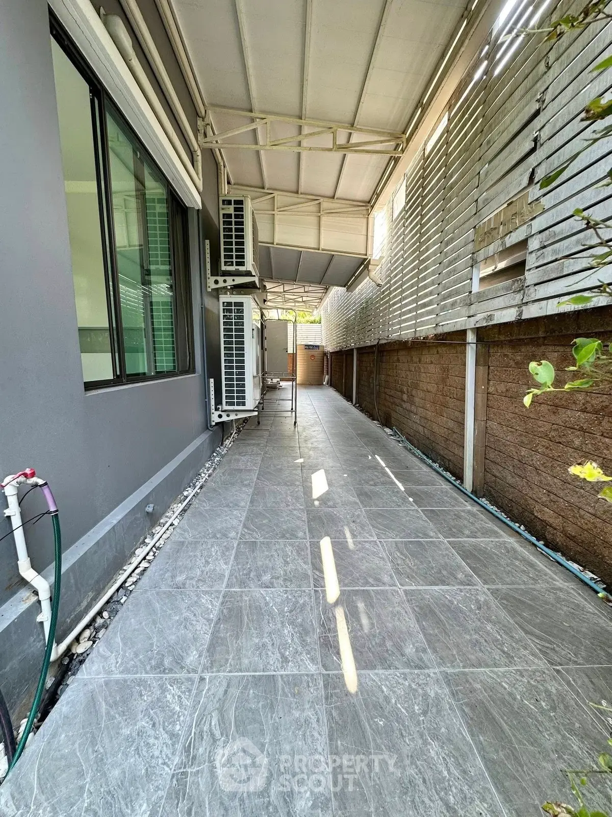 Spacious outdoor corridor with modern tiled flooring and privacy fencing