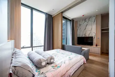 Luxurious bedroom with modern decor and city view, featuring a cozy bed and stylish TV setup.
