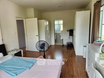 Spacious bedroom with wooden flooring and ample natural light