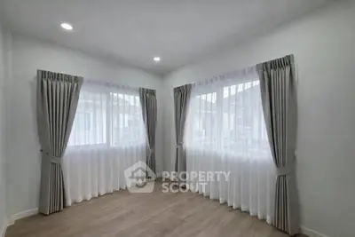 Bright corner room with large windows and elegant curtains, perfect for a cozy living space.