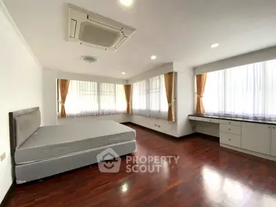 Spacious bedroom with hardwood floors and large windows for natural light.