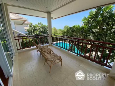 Spacious balcony with pool view and lush greenery, perfect for relaxation.