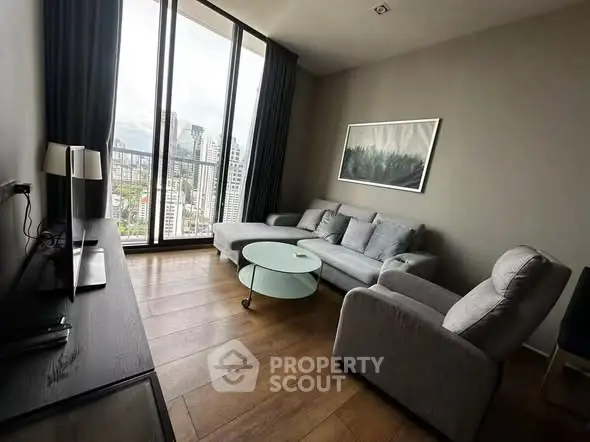 Modern living room with city view, featuring sleek furniture and floor-to-ceiling windows.