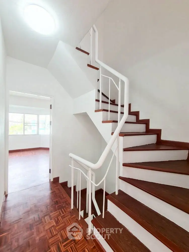 Elegant staircase with wooden steps leading to a bright room with large windows.