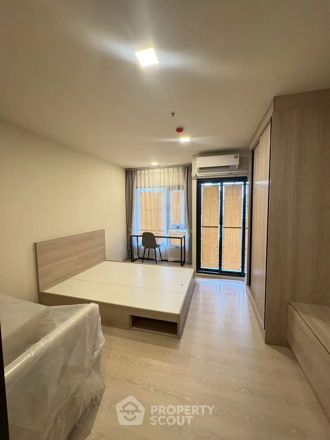 Modern bedroom with study area and balcony access in stylish apartment